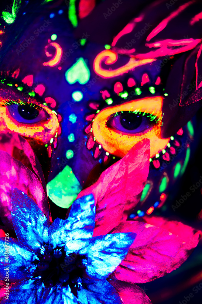 Anonymous female in multicolored masquerade mask with flowers on head looking at camera on Halloween night Anonymous female in multicolored masquerade mask with flowers on head looking at camera on Halloween night