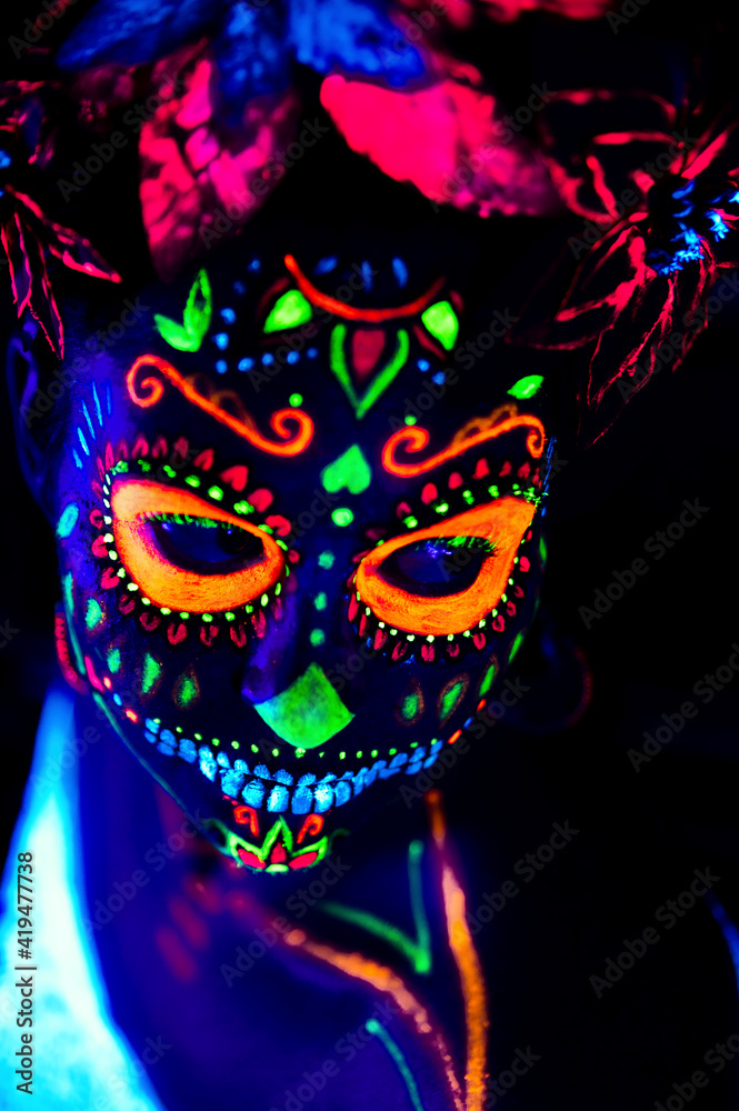 Anonymous female in multicolored masquerade mask with flowers on head looking at camera on Halloween night Anonymous female in multicolored masquerade mask with flowers on head looking at camera on Halloween night