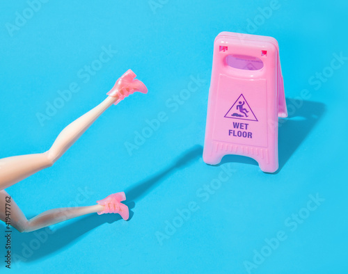 Attention! Slippery floor. A woman who slipped on a slippery floor and fell. Pastel blue background with pink elements. Minimal creative idea for caution. photo