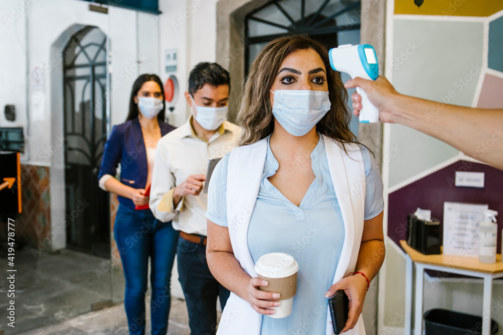 Office latin workers are checked with thermometer during coronavirus pandemic to prevent covid-19 in Latin America Office latin workers are checked with thermometer during coronavirus pandemic to prevent covid-19 in Latin America