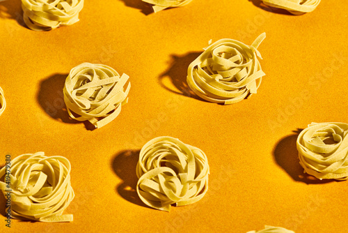 From above set of raw fettuccine pasta nests placed on bright yellow table