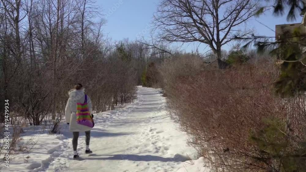 The girl carefully walks along the icy path in the park The girl carefully walks along the icy path in the park
