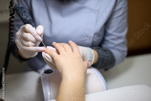 master makes the client a hardware manicure. The manicurist polishes the client's nails and prepares to apply gel polish