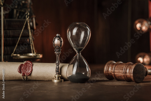 Hourglass, books and stamp on testament and last will in a courtroom.