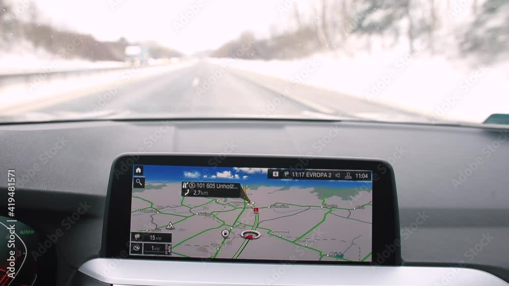 On-board computer screen of a car in motion. The navigation system shows the way. Road traffic in bokeh. Orientation of the direction of movement on the way.