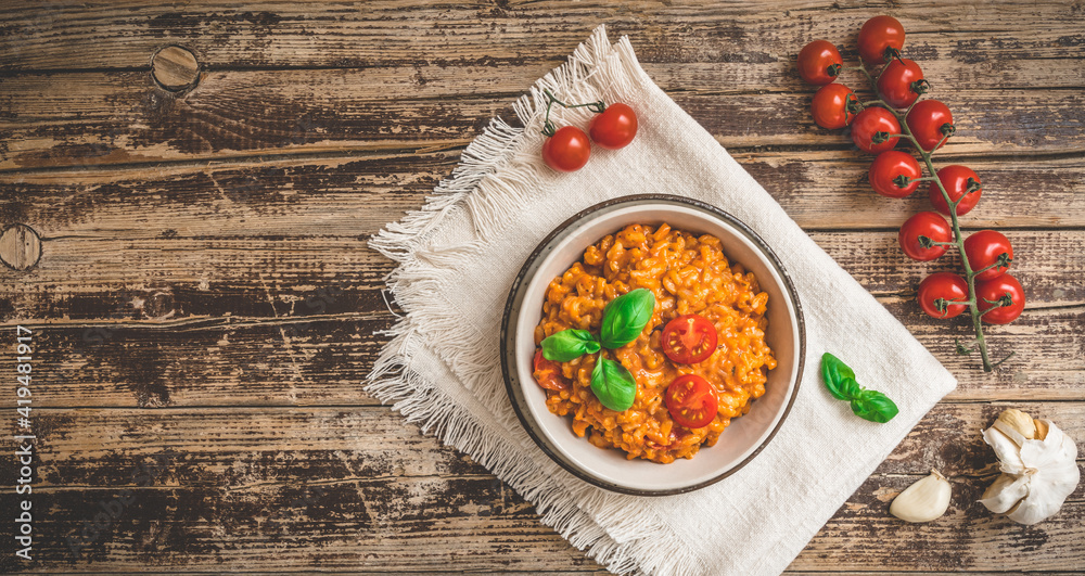 Homemade tomato risotto with fresh basil on a rustic wooden table, top view Homemade tomato risotto with fresh basil on a rustic wooden table, top view
