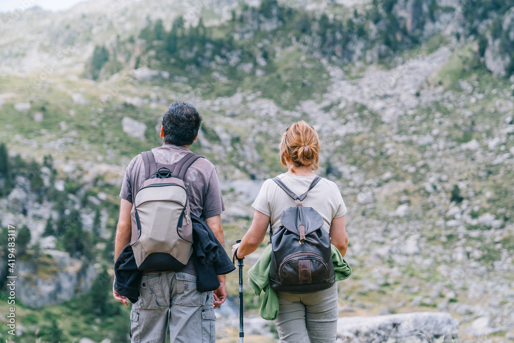 Back view of anonymous backpackers walking on mountain during summer trip Back view of anonymous backpackers walking on mountain during summer trip