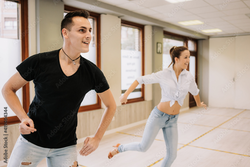 Talented couple performing ballroom dance while rehearsing in bright spacious studio with mirror during class Talented couple performing ballroom dance while rehearsing in bright spacious studio with mirror during class