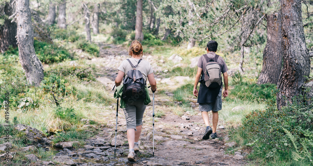 Back view of anonymous backpackers walking on mountain during summer trip Back view of anonymous backpackers walking on mountain during summer trip