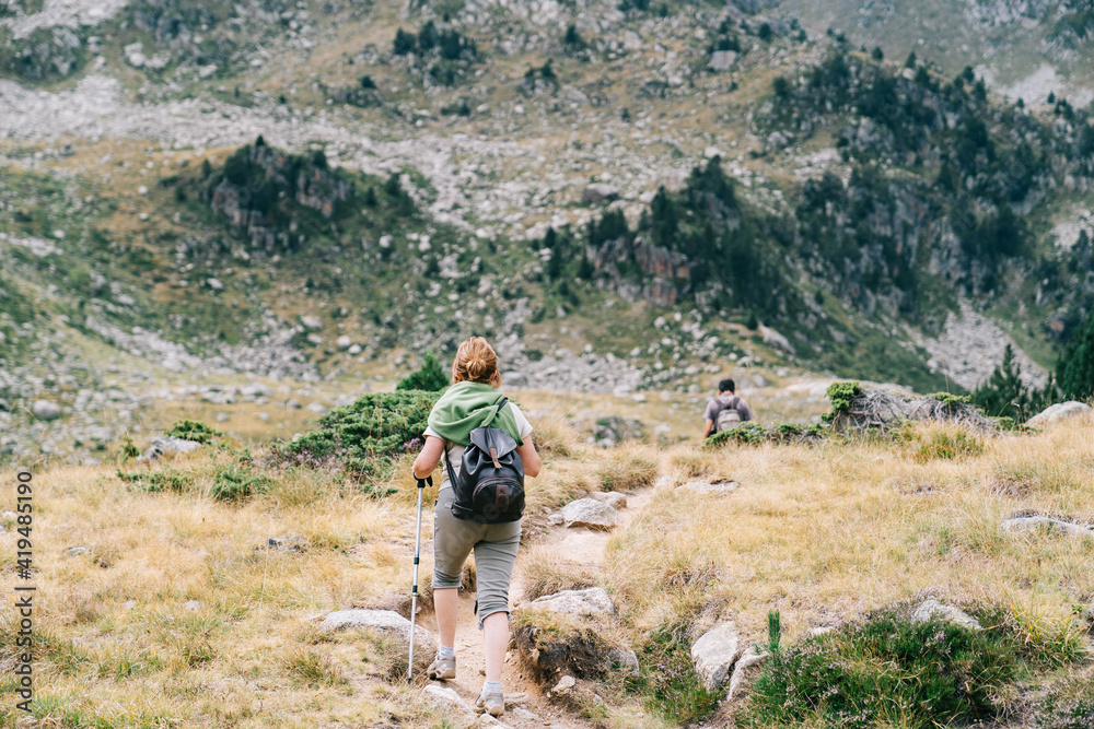 Back view of anonymous backpackers walking on mountain during summer trip Back view of anonymous backpackers walking on mountain during summer trip