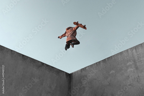 From below full body back view of young skater in casual clothes with skateboard jumping on concrete ramp in skate park performing trick photo