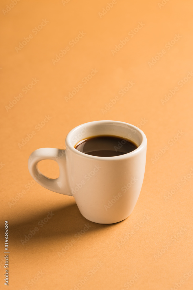 High angle of white ceramic cup with hot aromatic coffee placed on bright colorful background High angle of white ceramic cup with hot aromatic coffee placed on bright colorful background