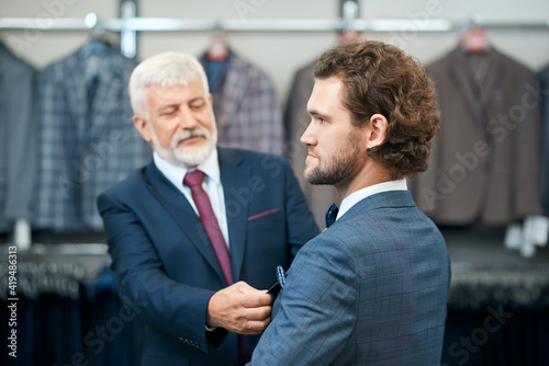 Father choosing costumes for son in store.