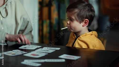little boy learns words from cards under the ABA therapy program at home at the table