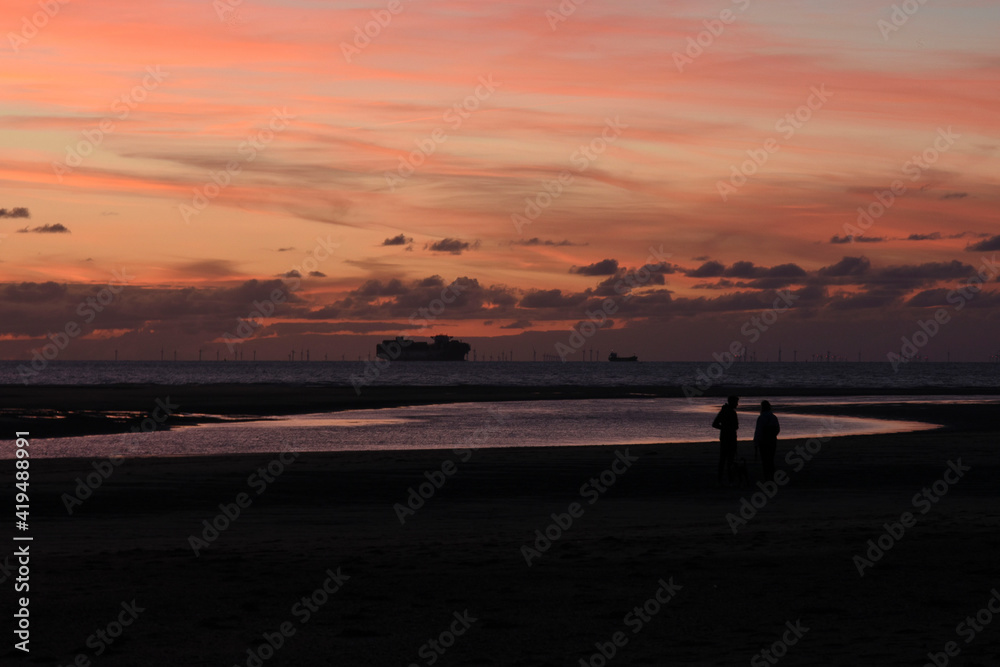silhouettes of couple and boats on sunset beach Cadzand silhouettes of couple and boats on sunset beach Cadzand
