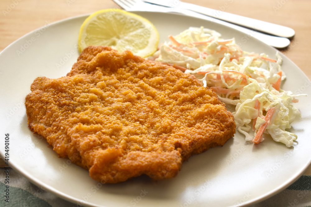 Pork Schnitzel with coleslaw and lemon on a plate. Pork Schnitzel with coleslaw and lemon on a plate.