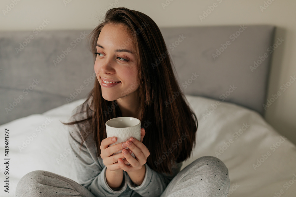Close up shot of smiling charming lady in home suit with cup of tea in the morning Close up shot of smiling charming lady in home suit with cup of tea in the morning