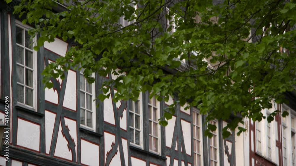 Tilt Down: Timbered Medieval Buildings With Narrow Windows In Sunshine Partially Obscured By Lush Tree Foliage Tilt Down: Timbered Medieval Buildings With Narrow Windows In Sunshine Partially Obscured By Lush Tree Foliage