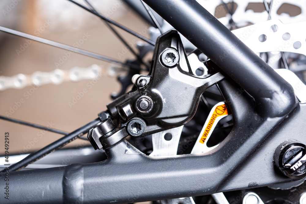 Obraz premium Modern Rear disk brake on a mountain bike with black frame close up detail