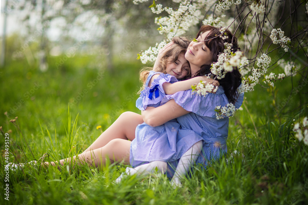 happy mom and daughter in the spring blooming garden playing together happy mom and daughter in the spring blooming garden playing together