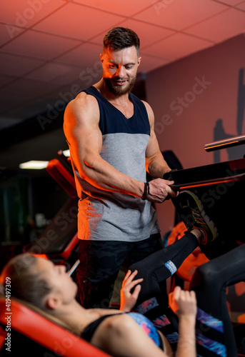 Sporty man and woman doing exercises in contemporary gym. Personal trainer conducts sportive course. Active way of life.