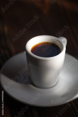 A cup of aromatic black coffee. Morning espresso or Americano coffee for breakfast in a beautiful cup. Wooden background. 