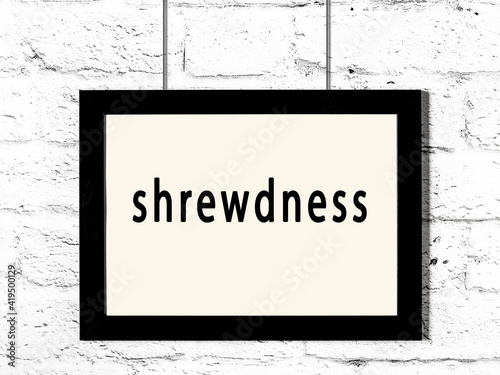Black frame hanging on white brick wall with inscription shrewdness