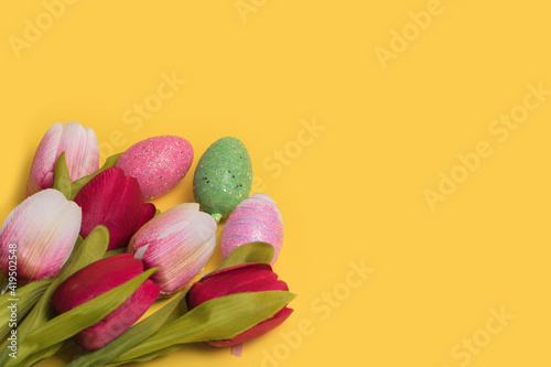 Creative Easter decotation made of colorful eggs and tulips on illuminating yellow background. photo