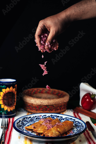 chef serving onion over the cochinita pibil tacos