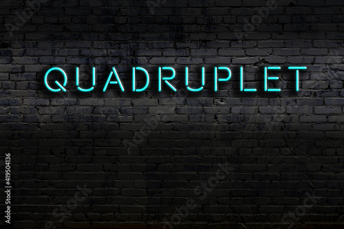 Night view of neon sign on brick wall with inscription quadruplet