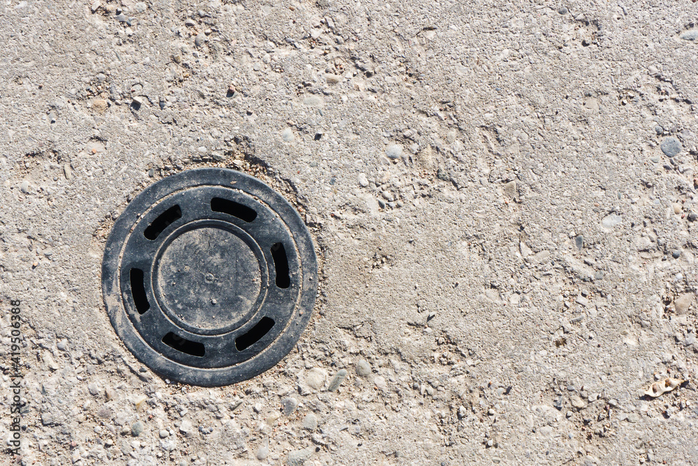 Round manhole on concrete drain system cover. Urban sewer background