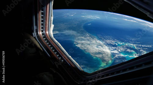 Fototapeta Naklejka Na Ścianę i Meble -  Spaceship flies near the amazing blue planet earth, view from the window. Travel and tourists in space, concept. Beautiful space view of the Earth with cloud formation. Hotel in space