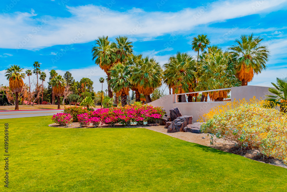 The entrance to Palm Springs is surrounded by flowers and Palm Trees.