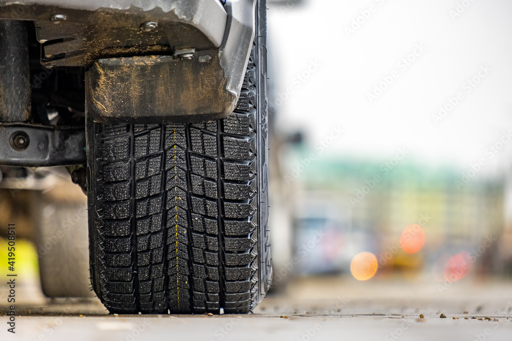 Closeup of parked car on a city street side with new winter rubber tires. Closeup of parked car on a city street side with new winter rubber tires.