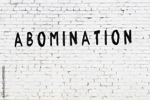 Tableau sur toile White wall with black paint inscription abomination on it
