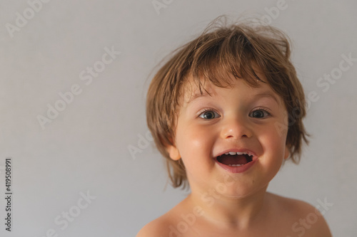 precioso y guapo bebé bajo fondo blanco con preciosa sonrisa y pose natural enseñando los dientes y una increíble sonrisa.