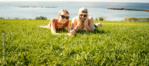 Smiling happy couple lying on the grass, enjoying free time. photo