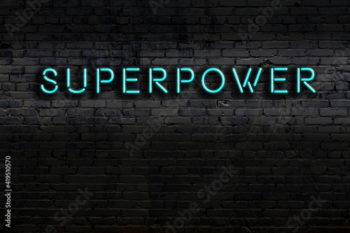 Night view of neon sign on brick wall with inscription superpower photo