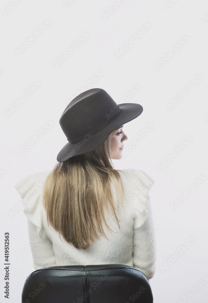 girl in a white sweater posing in a felt hat on a light background girl in a white sweater posing in a felt hat on a light background