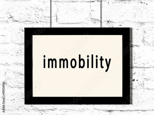 Foto Black frame hanging on white brick wall with inscription immobility