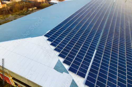 Aerial view of surface of blue photovoltaic solar panels mounted on building roof for producing clean ecological electricity. Production of renewable energy concept.