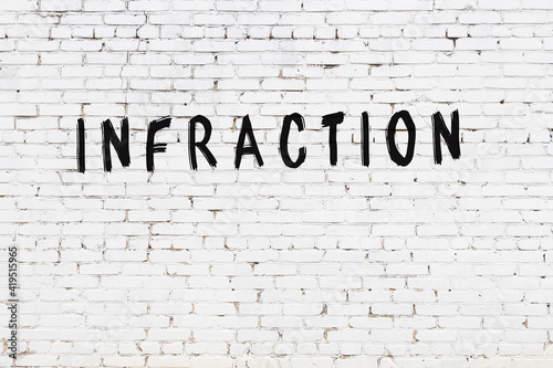 Inscription infraction painted on white brick wall