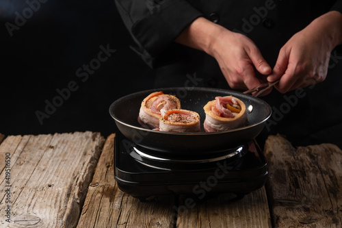 Chef prepares meat steaks in bacon, beef or pork. Chef on black background for restaurant menu text copy space