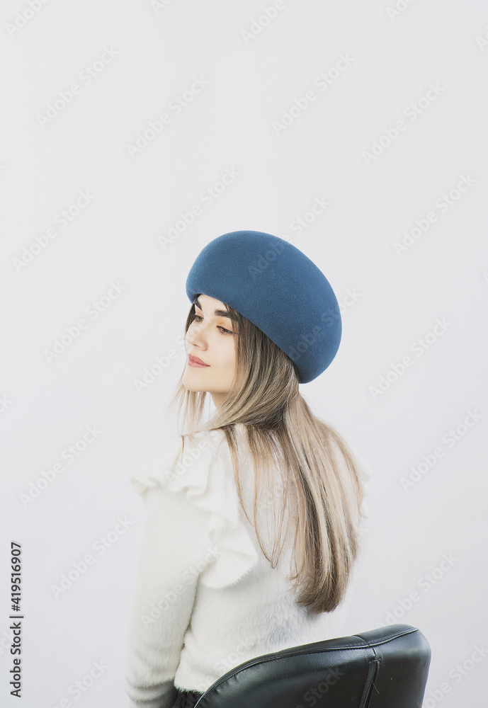girl in a white sweater posing in a felt hat on a light background girl in a white sweater posing in a felt hat on a light background