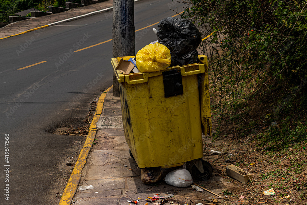 Cesto de lixo cheio com roda quebrada em esquina na descida de rua Stock  Photo | Adobe Stock