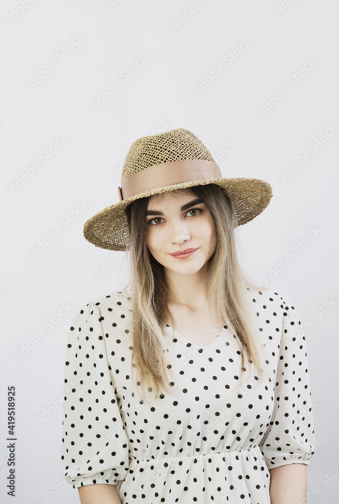 girl in a sundress and straw hat posing on a light, solid background girl in a sundress and straw hat posing on a light, solid background