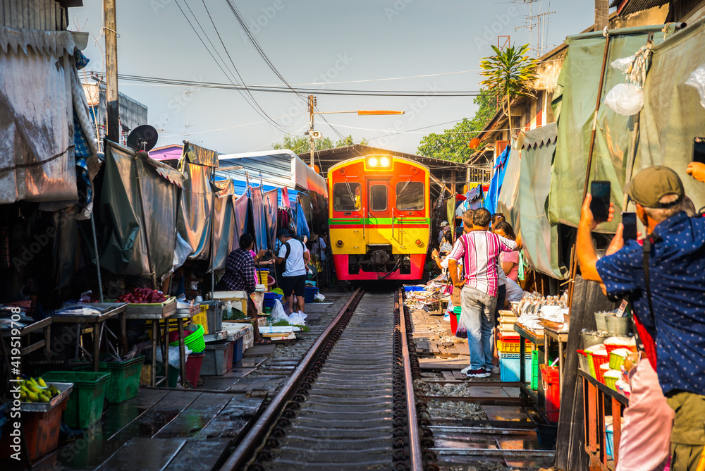 Train on Tracks Moving Slow. Umbrella Fresh Market on the Railroad Track, Mae Klong Train Station, Bangkok, Thailand on a Sunny Day.