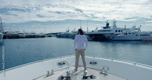 Handsome man from behind standing on a boat sailing into the seagate - Cinematic scene with RED Camera 4K photo