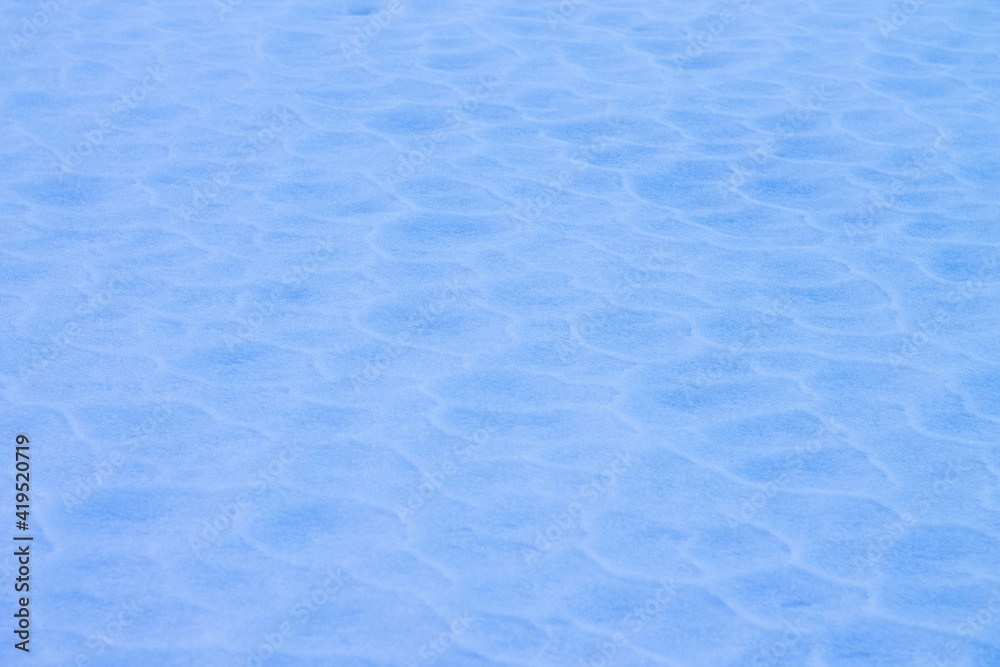 Background texture of blue snow covered with waves due to wind