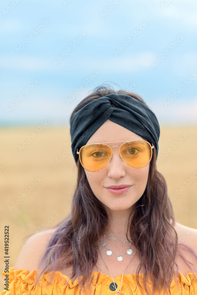 Brunette girl with closed eyes in green linen headband, orange dress, and yellow glassed closeup Brunette girl with closed eyes in green linen headband, orange dress, and yellow glassed closeup